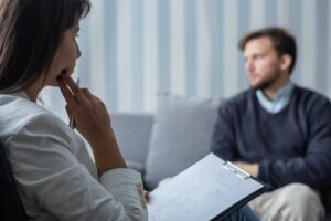 Thoughtful psychotherapist during session with sad patient with
