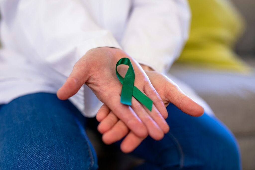 Midsection of mature caucasian female doctor showing mental health awareness ribbon