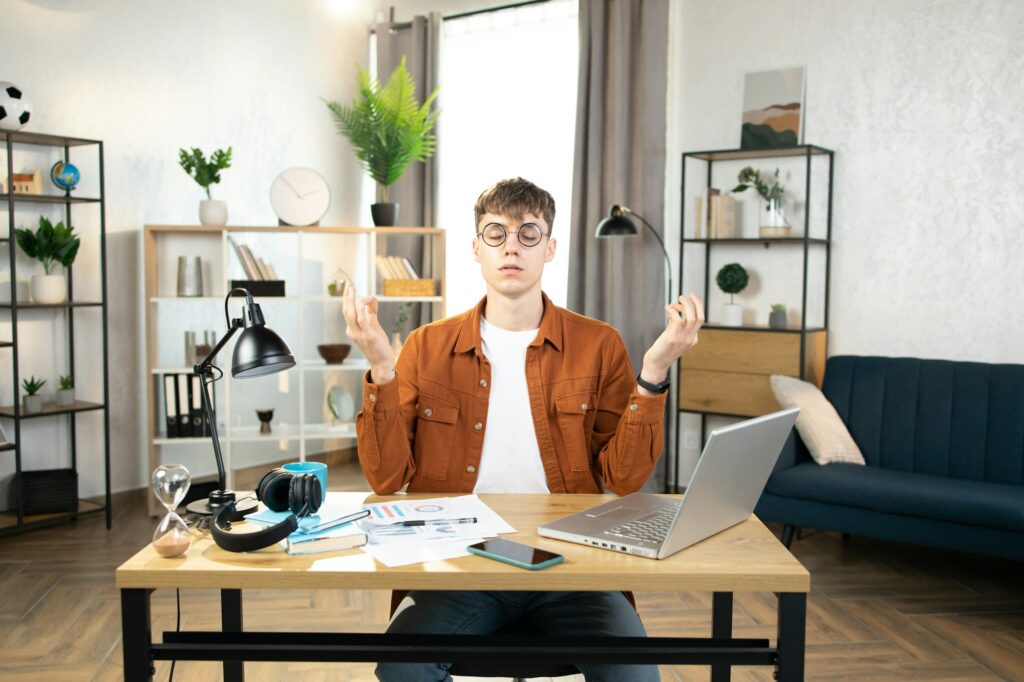 Relaxed Caucasian man meditating at workplace at home