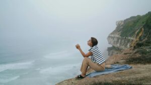 Thinking girl relaxing ocean cliff alone. Serene woman enjoying seashore waves